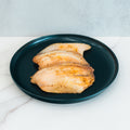Three pieces of Baked Herbed Tilapia 1lb Competition Approved are arranged on a dark green plate atop a white surface with a light gray background—ideal for meal prep or supporting your weight loss goals.