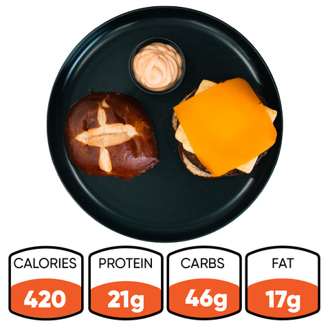 A high-protein breakfast twist: the Vegan Breakfast Sandwich on a pretzel bun with sauce, served on a black plate. With 420 calories, 21g protein, 46g carbs, and 17g fat, this healthy vegan option is an energizing way to start your day.
