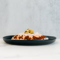 The Vegan Cheeseburger Bowl features white rice, saucy Beyond Beef, shredded cheese, orange sauce, and relish on a black plate—set against a light gray background, making it perfect for vegan meal prep bowls.