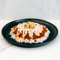 The Vegan Cheeseburger Bowl features white rice, seasoned Beyond Beef, shredded vegan cheese, creamy orange sauce, and chopped pickles—all served on a black plate for a mouthwatering plant-based meal.
