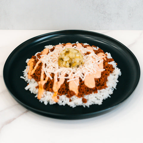 The Vegan Cheeseburger Bowl features white rice, seasoned Beyond Beef, shredded vegan cheese, creamy orange sauce, and diced pickles—delicious and perfect for vegan meal prep.